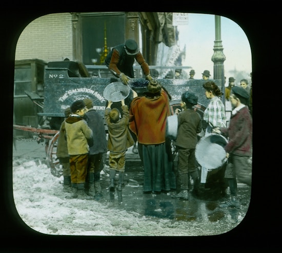 Lantern slide showing women and children with empty large pans. One woman is receiving a full pail of coal. Probably in NY