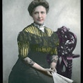 Kate Adams Keller facing right with bun in hair in a color lantern portrait.