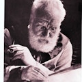 Elderly Alexander Graham Bell writing and holding pipe.