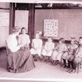 Six Horace-Mann students sit semi-circle around a teacher while one student stands left.