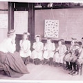Six deaf students all sitting facing camera in classroom while one female teacher instructs the lesson.