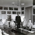 Horace Mann students and teacher stand behind desks and chairs, facing the camera in a classroom.