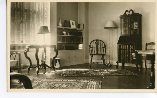 Parlor at the Wright Oral School with a chair, small table with lamp near window, and bookshelf.