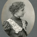 Helen Keller wearing lace collared dress with hair in a bun facing right in a head and shoulders portrait.