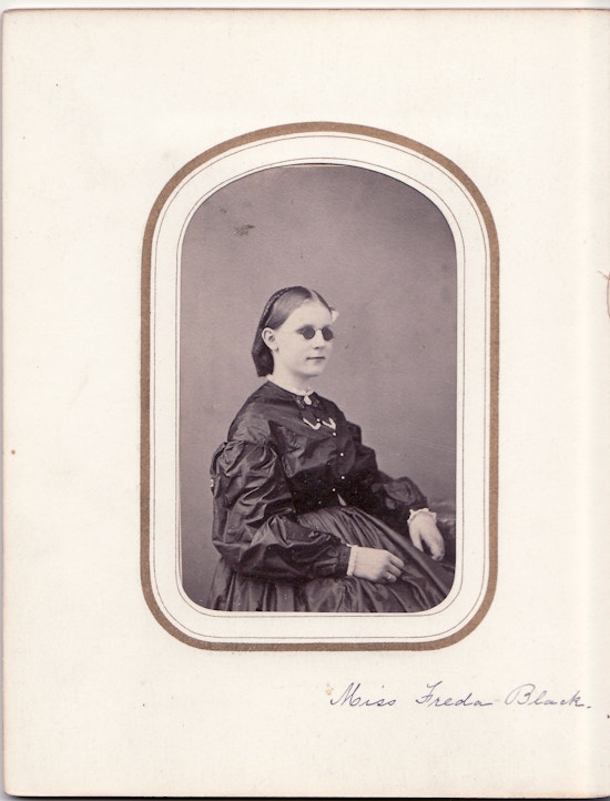 Miss Freda Black, sitting portrait, dark dress, dark glasses.