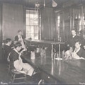 male students seated around table with science experiments, holding chemistry beakers.