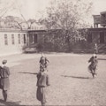 Children playing potato sack race with guiding cables, background shows Perkins entryway portico.