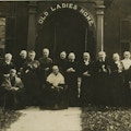A group of two dozen elderly women under a sign saying Old Ladies Homes.