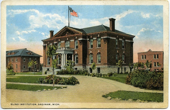 Blind Institute, Saginaw, Michigan. A two-story brick building with an American flag on top.