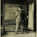 Man writing on a blackboard with his left hand.