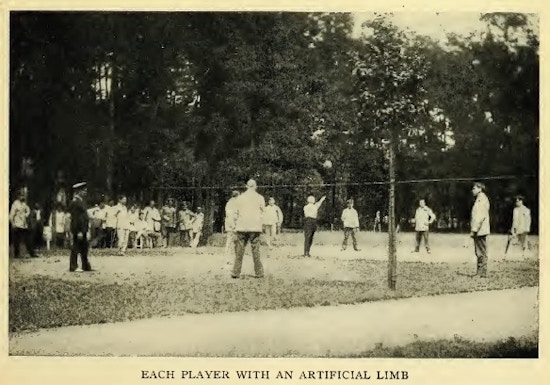 Group of amputees playing volleyball in a field.