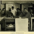 Men sitting around a table learning bookbinding.