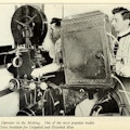 Two men using movie projection equipment.