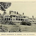 Photograph of large sprawling building with many windows, porches, and decks.