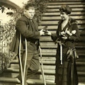Mrs. Coolidge presents a medal to a man (L.B. Clark) on crutches.