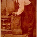 Sepia toned photo of man hunched over holding a cane.