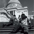 Two young people crawl up the steps of the Capitol Building.