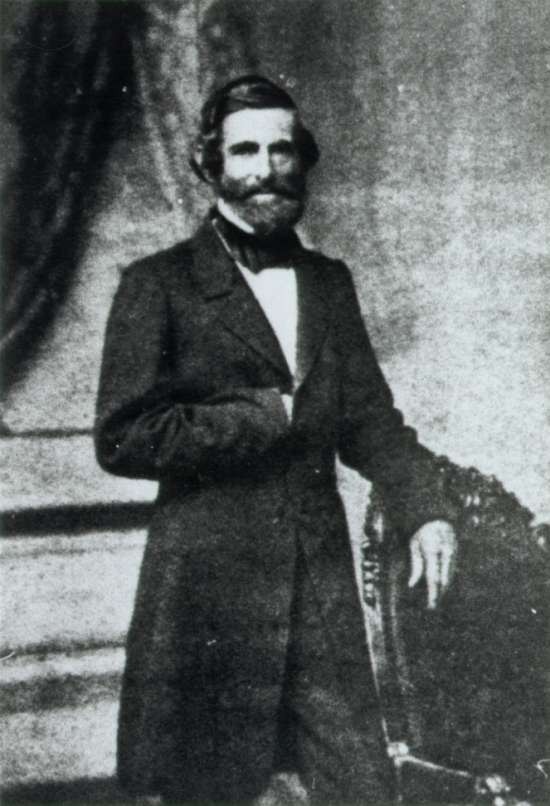Photograph of Samuel G. Howe leaning on a chair with his right hand resting in his buttoned coat.