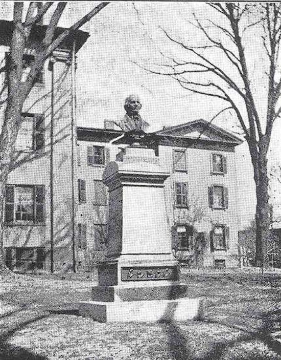Bust of Laurent Clerc atop pedestal in front of large building