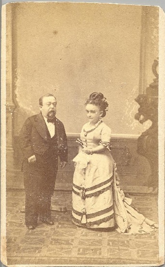 A short-statured man and woman, both formally dressed.