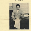 A young man sits in a chair and reads a book.