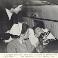 A man with a respirator attended by a nurse on a plane.