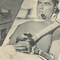 A man with a telephone headset and a respirator chestpiece.