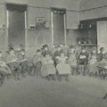 A group of boys and girls in a semi-circle engaged in sewing.