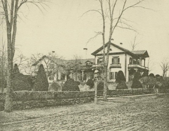 A large house with fence and elm trees.