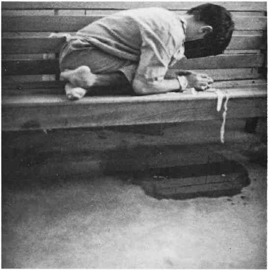A boy tied to a wooden bench.
