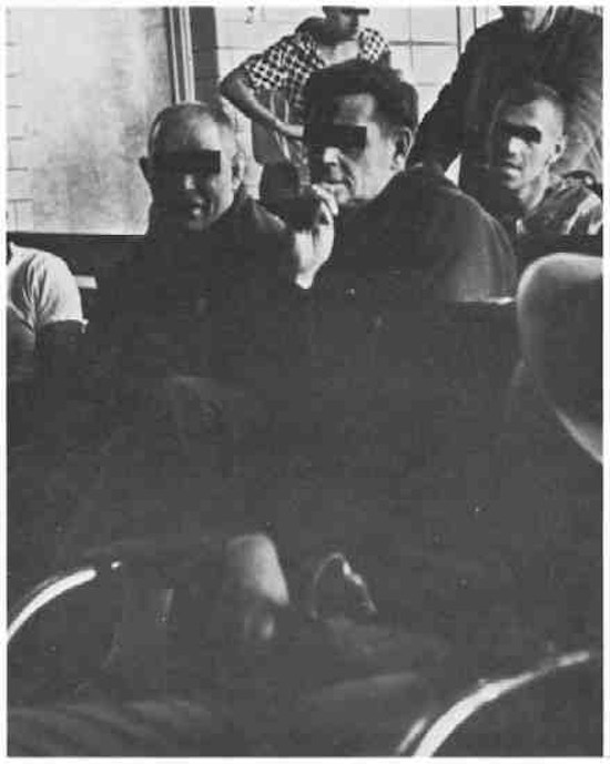 Men on a ward, some sitting on a bench.