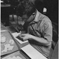 A young man gluing paper.