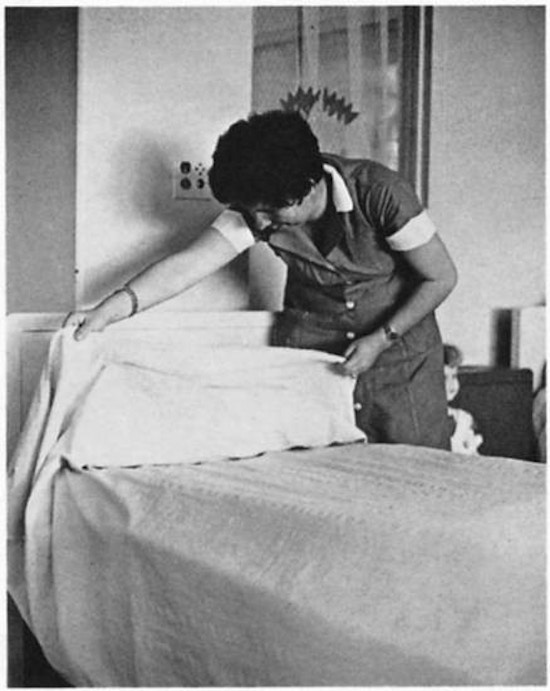 A woman making a bed.