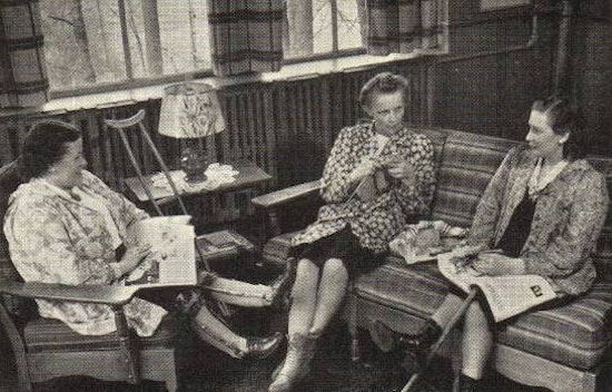 Three women sits and talk. One has a crutch and braces. Another has a cane.
