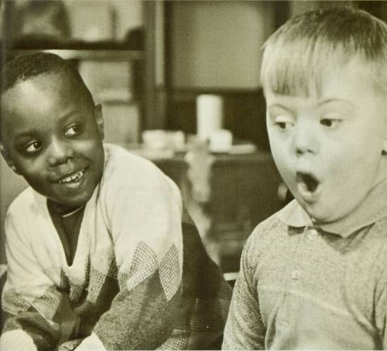 Two boys, One African American and the other white.  One smiles and the other appears to be singing.