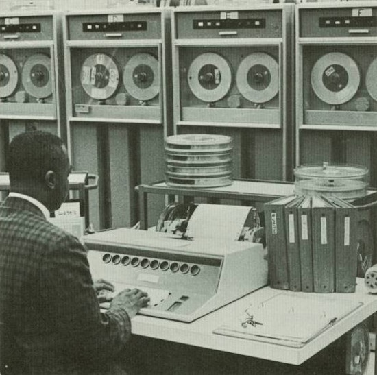 An African American man works at an early computer.