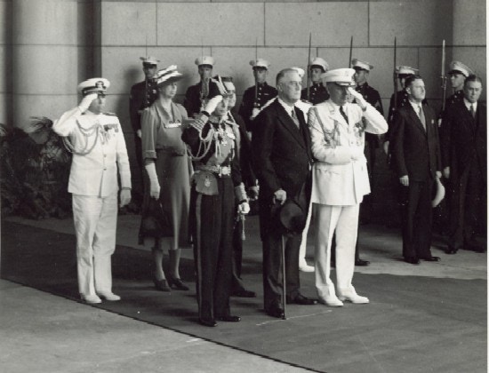 King George, Franklin Roosevelt, Eleanor Roosevelt stand with military personnel, many saluting, at Union Station.