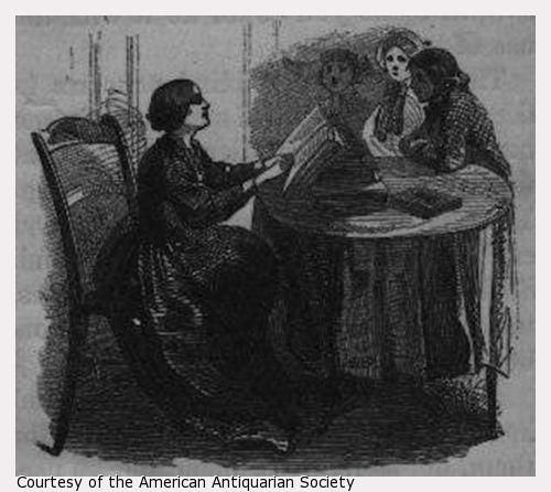 Woman sitting in chair at table reading book to three girls