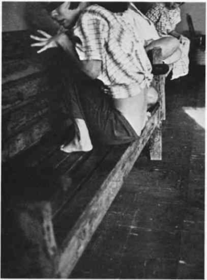 Woman crouching on a wooden bench.