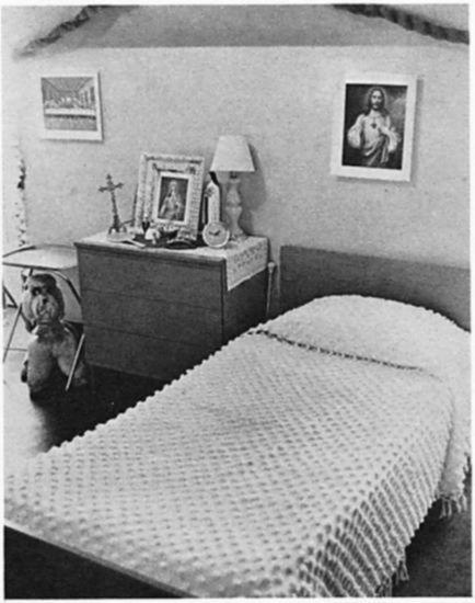 A room with a bed, a bureau, images of Jesus, a crucifix, and a stuufed animal.