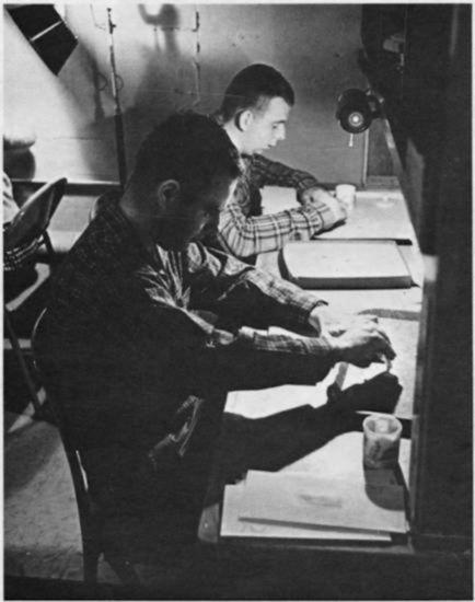 Two young men sitting at a table with trays.