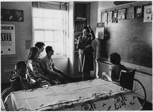 A teacher with four children in a classroom.