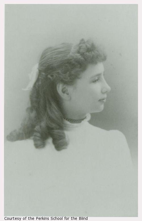 Young Helen Keller facing right, white bow in hair, white dress.