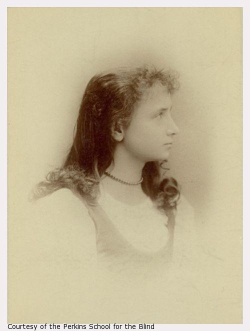Young Helen Keller, side view looking right, white dress, necklace, hair down loosely arranged.