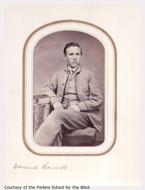 Edward Howarth, seated portrait, light suit, legs crossed.