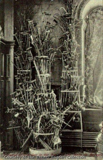 Photograph of a large pyramid of Crutches in the corner of a church.
