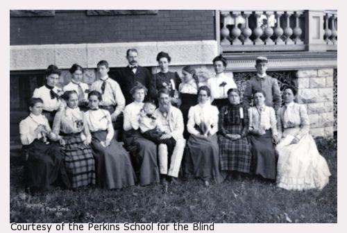 Gathering of pupils with deafblindness and teachers from five institutions in Buffalo, New York in 1901. Reunion funded by William Wade. Students and teachers are arranged in two arching lines outside on the grass with front row seated and back row standing. From the Perkins School for the Blind: Edith M. Thurston, Thomas Stringer, Miss Helen S. Conley, Edith Thomas, Vina C. Badger, and Elizabeth Robin. From the South Dakota School for the Blind: Dora Donald (Superintendent) and Linnie Haguewood.From the Ohio Institute for the Deaf: Ada Buckles, Ada E. Lyon, and Leslie F. Oren. From the New York Institute for the Deaf: Myra L. Barrager, W. H. Van Tassell, Orris Benson, Catherine Pederson, Florence G. S. Smith and Katie McGirr.
