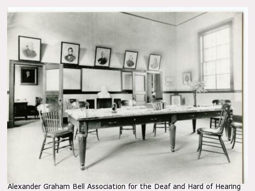 A laboratory room at the Volta Bureau with pictures, a large table, and chairs surrounding the table.