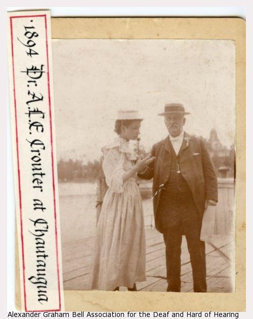Helen Keller in lightly colored dress wearing a hat and to the left of Dr. A.L.E. Crouter, wearing a suit and hat, at Chautauqua.