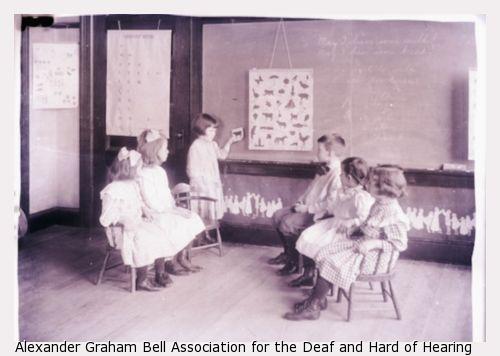 One student standing at the chalkboard and five students in the classroom sitting at the Horace Mann School.